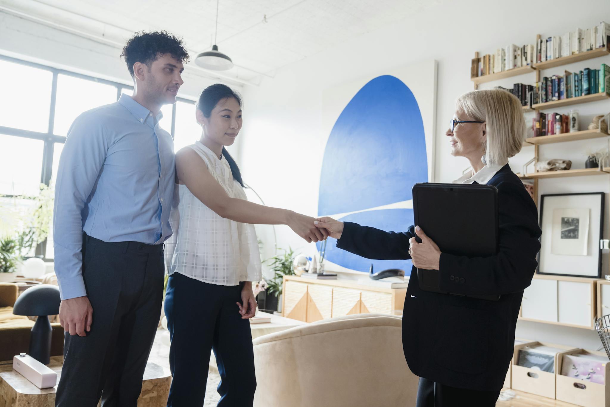 A therapist shakes hands with a couple after a successful therapy session.