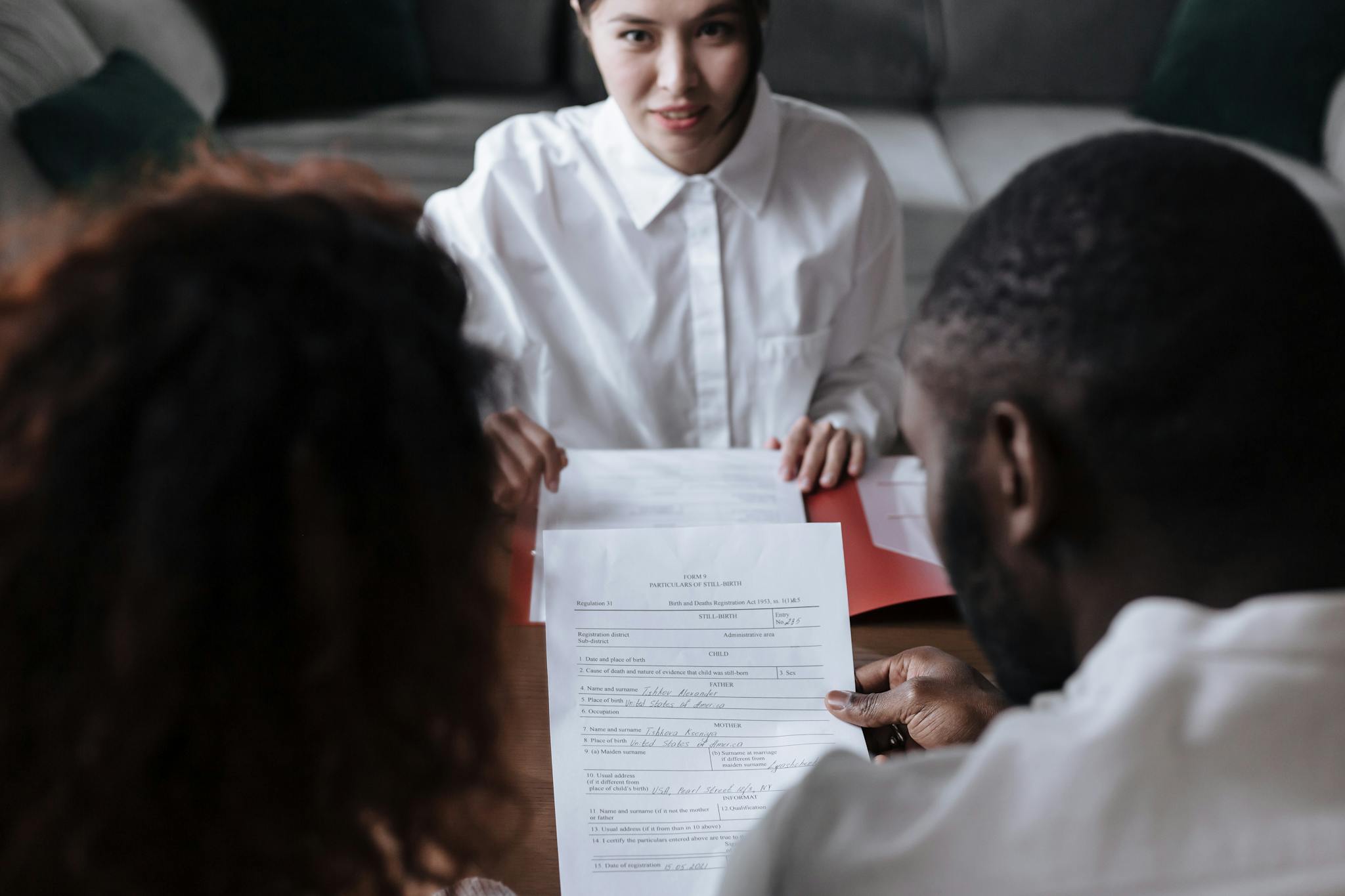 Three people reviewing documents in an office setting, focusing on adoption paperwork.